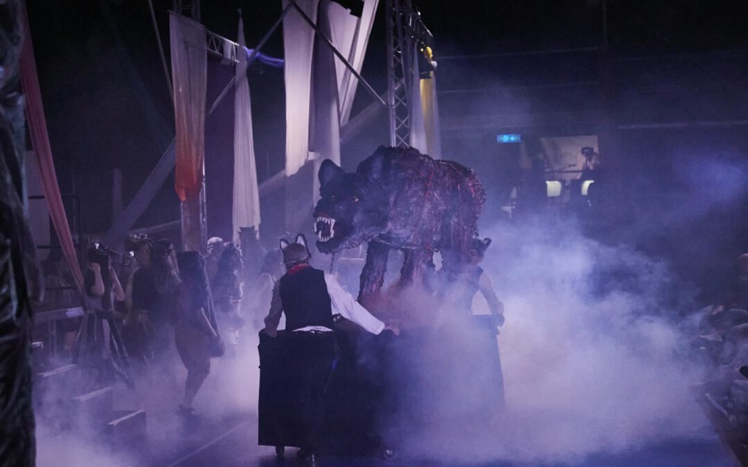 Lycantropia - Kein Weg zurück (2024) Große Wolfsstatue auf einem Wagen, Nebel und mehreren Personen in dunkler Umgebung beten diese Figur an auf der Bühne.