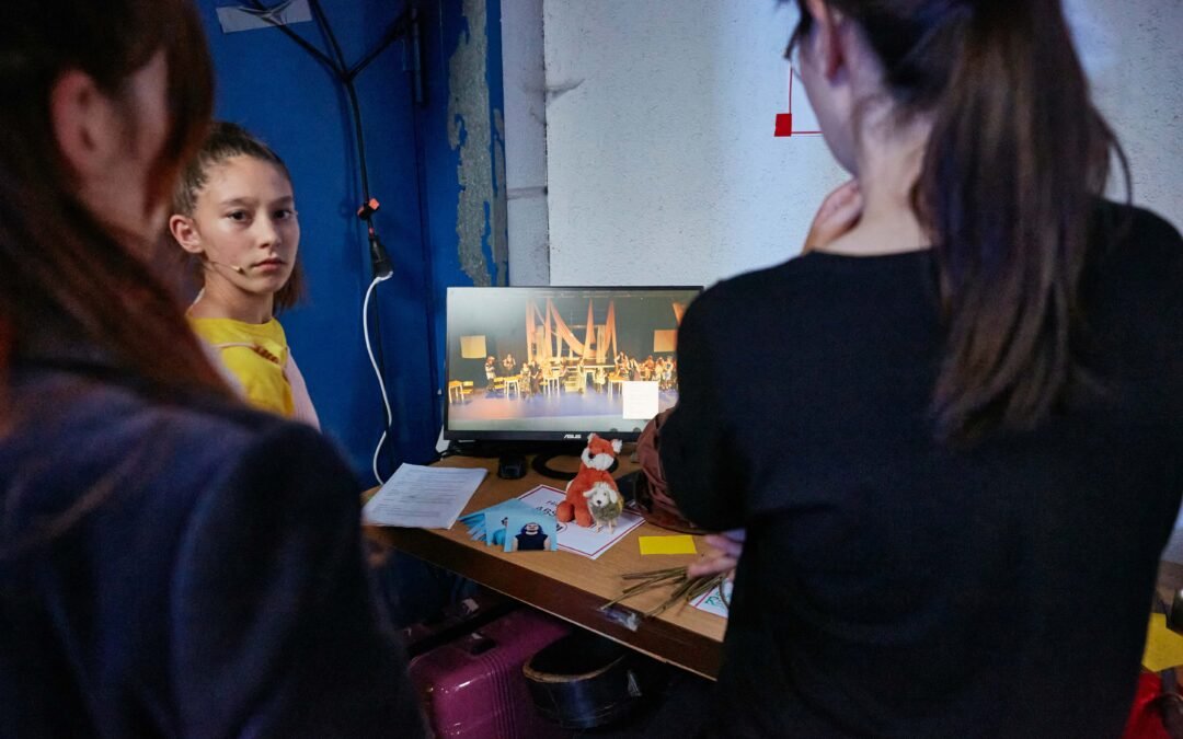Backstage-8 Drei Personen von hinten betrachten einen Monitor, der das Geschehen auf der Bühne zeigt